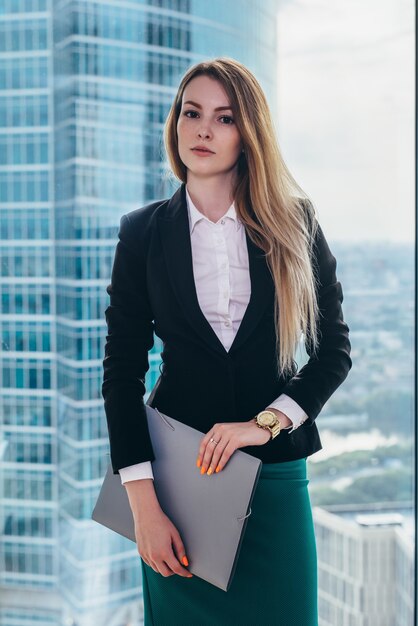 portrait-young-successful-businesswoman-standing-her-office-against-window_141192-2005